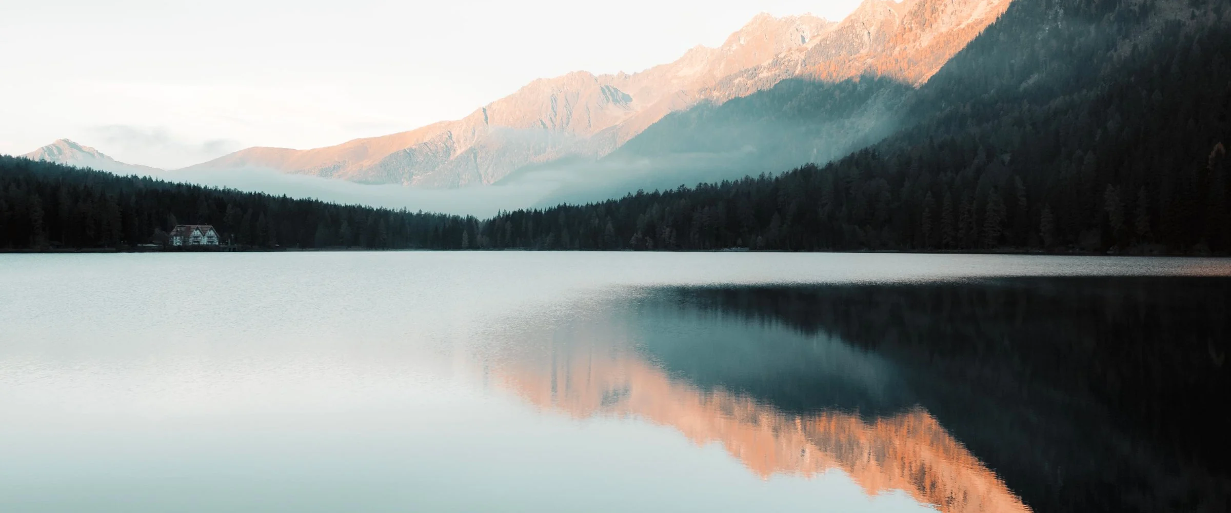 A still alpine lake at dawn reflecting the mountains around it